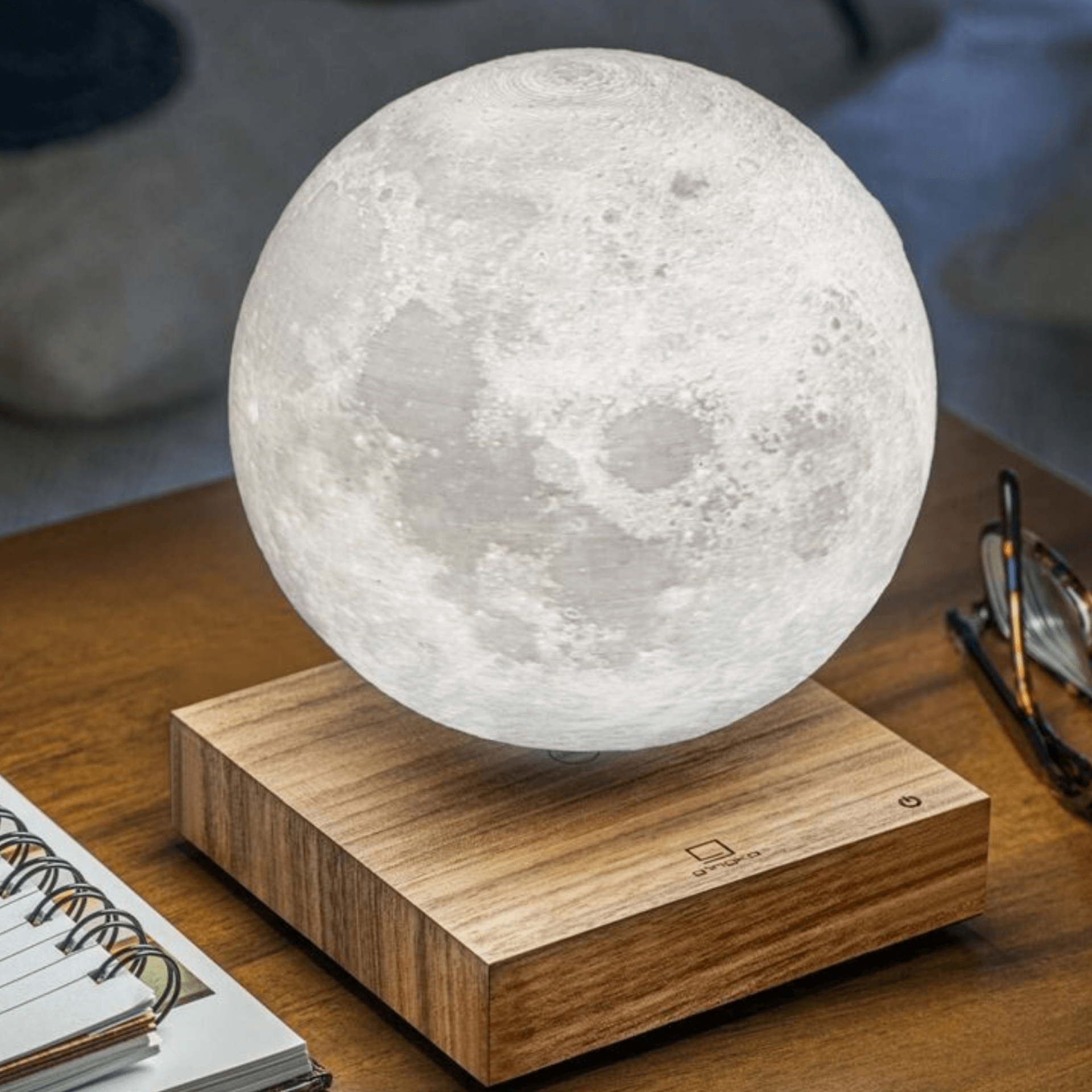 A floating moon lamp is sitting on a wooden table.
