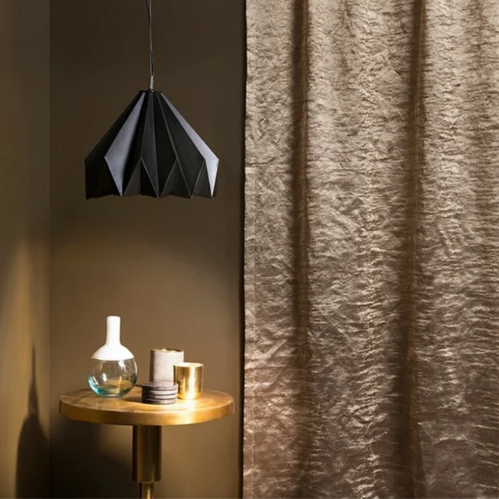 A table with a vase and candles on it next to a curtain