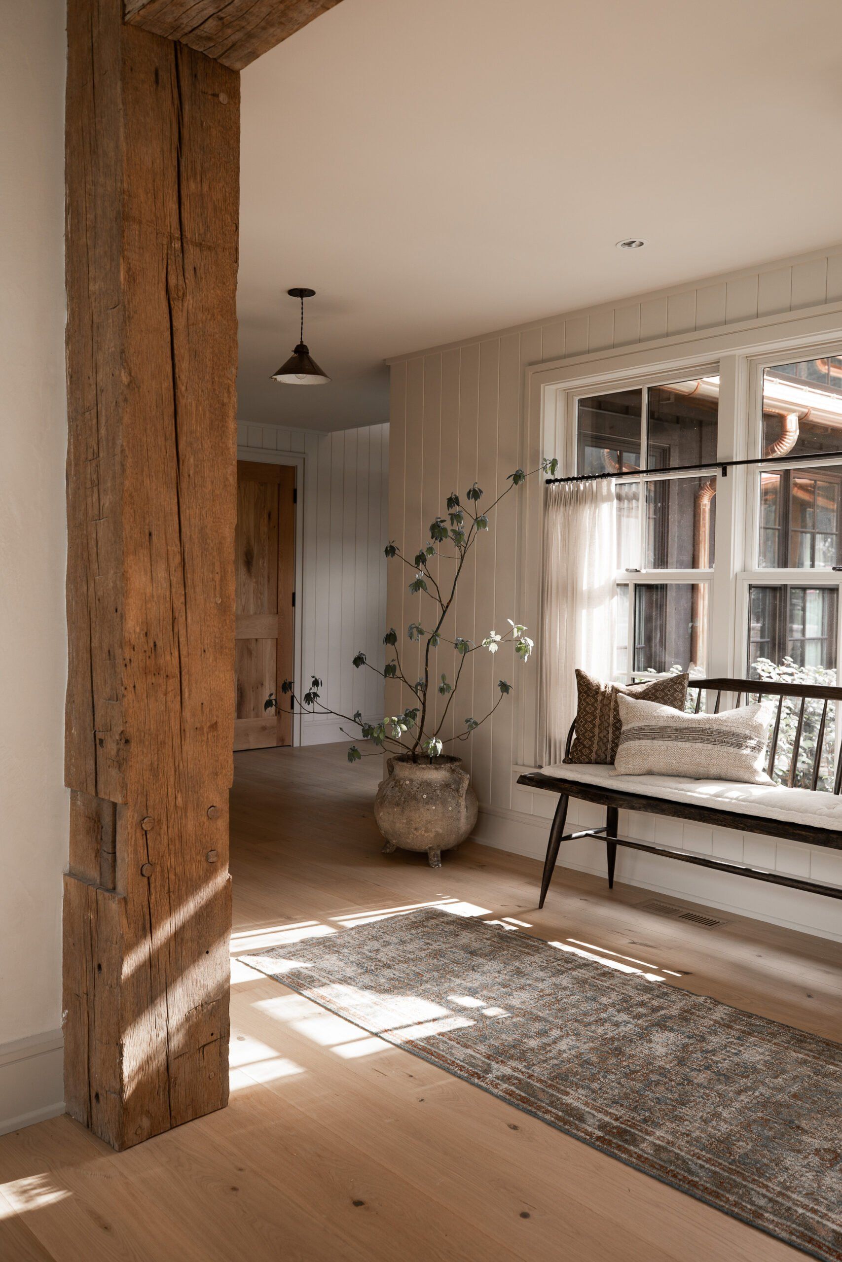 A hallway with a wooden beam and a bench.