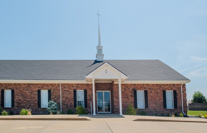 A brick church with a steeple and a cross on top of it.