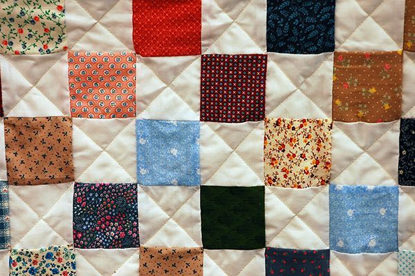 a close up of a quilt with many different colored squares