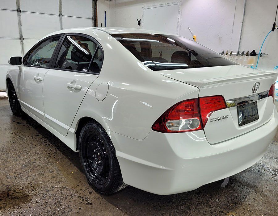 White Honda Civic sedan in a car wash, rear view.
