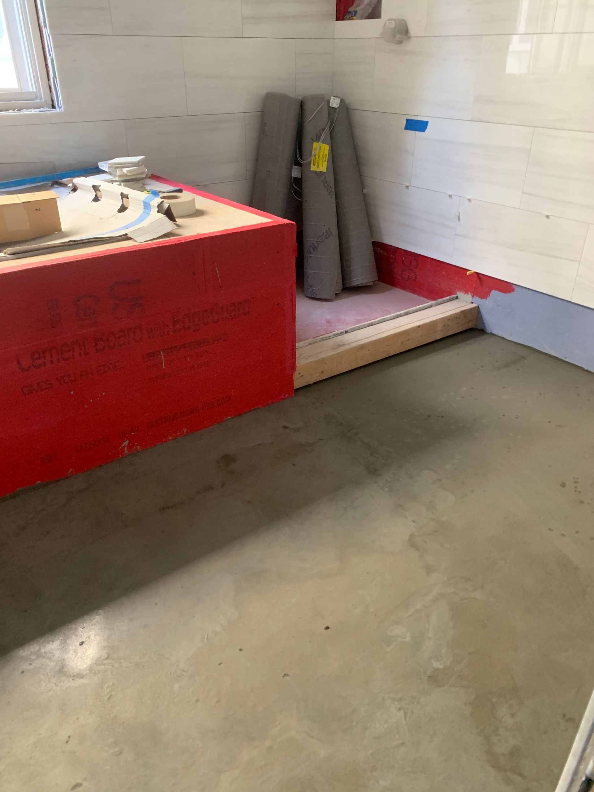 A room with a concrete floor and a red box on the floor.