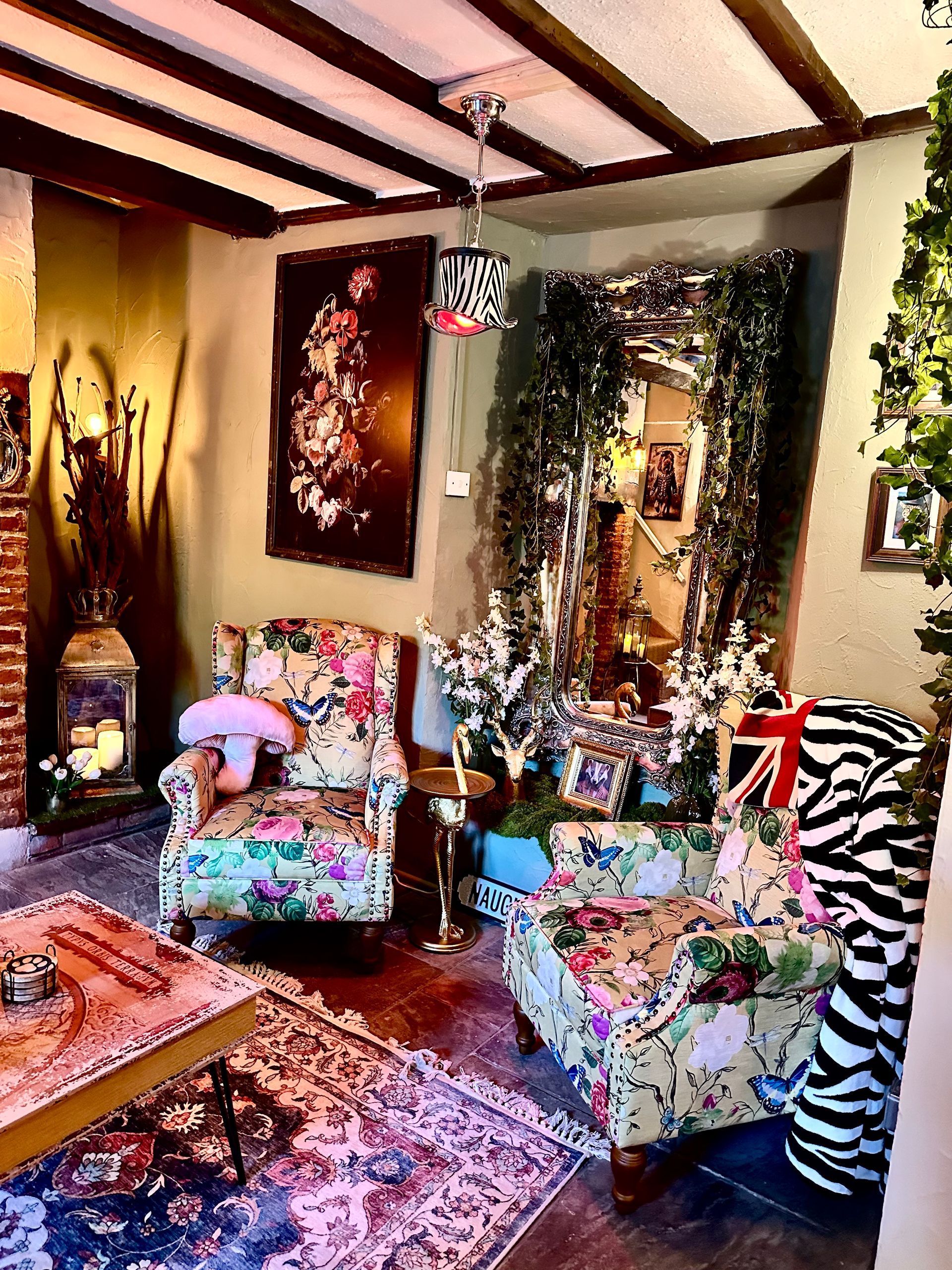 Colorful living room with patterned chairs, wooden beams, artwork, and a glass coffee table