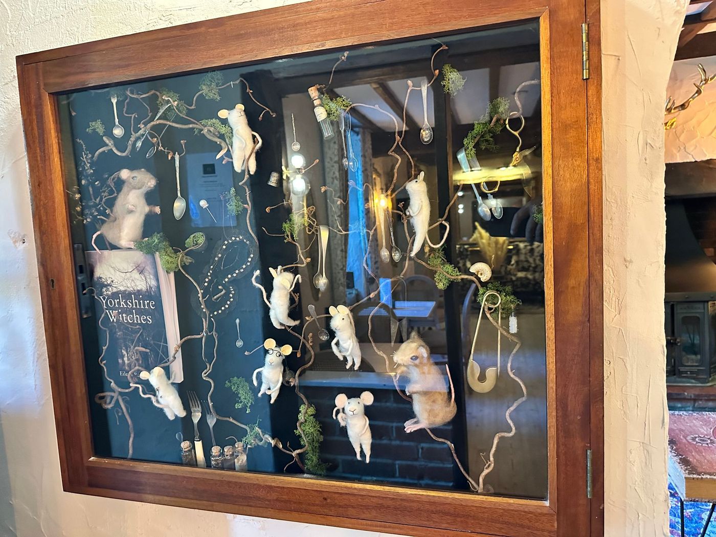 Framed display of white birds and string lights against a dark blue background in a wooden wall niche