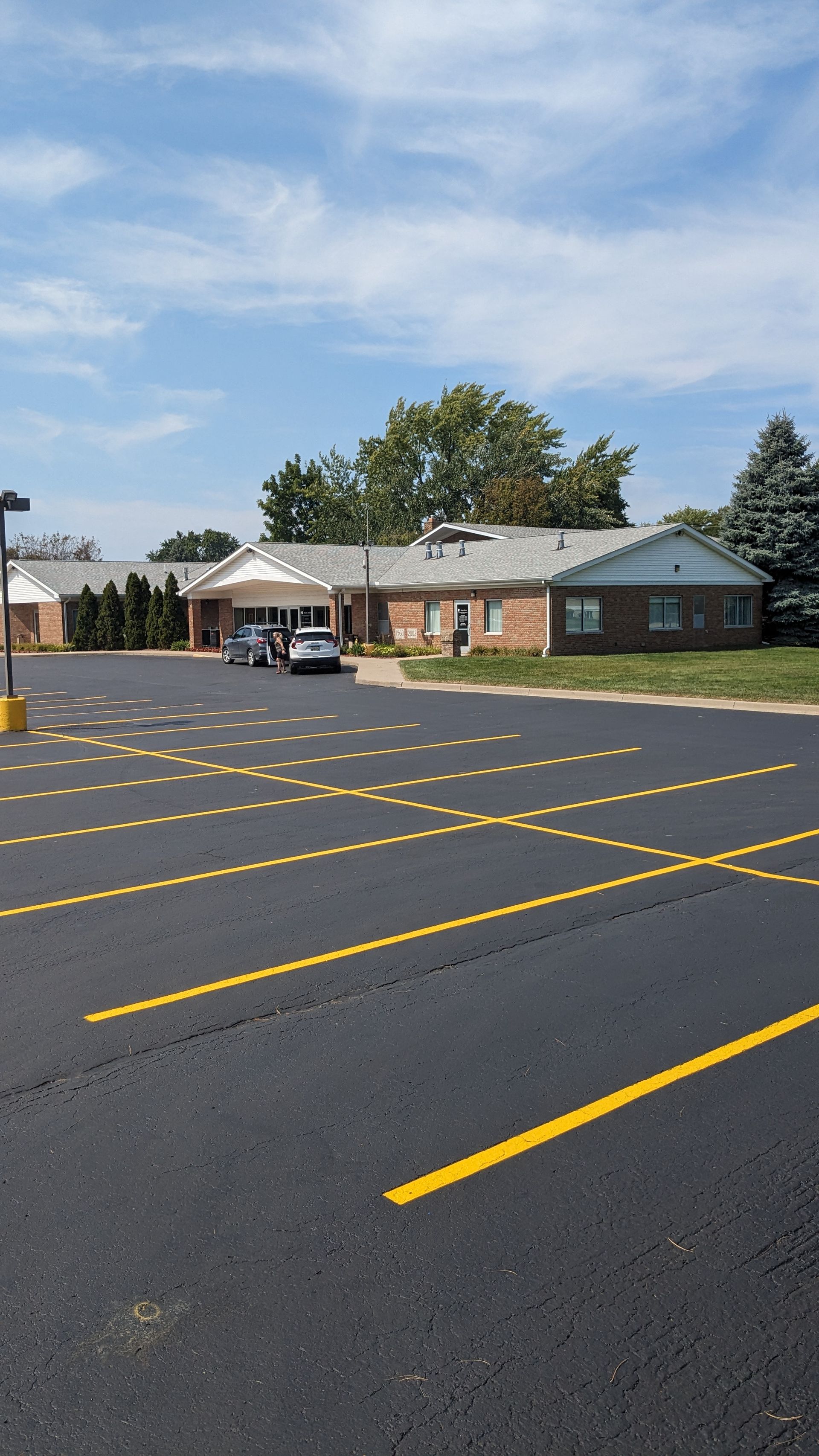 Building with a parking lot and a blue sky. Cars are parked in the lot.