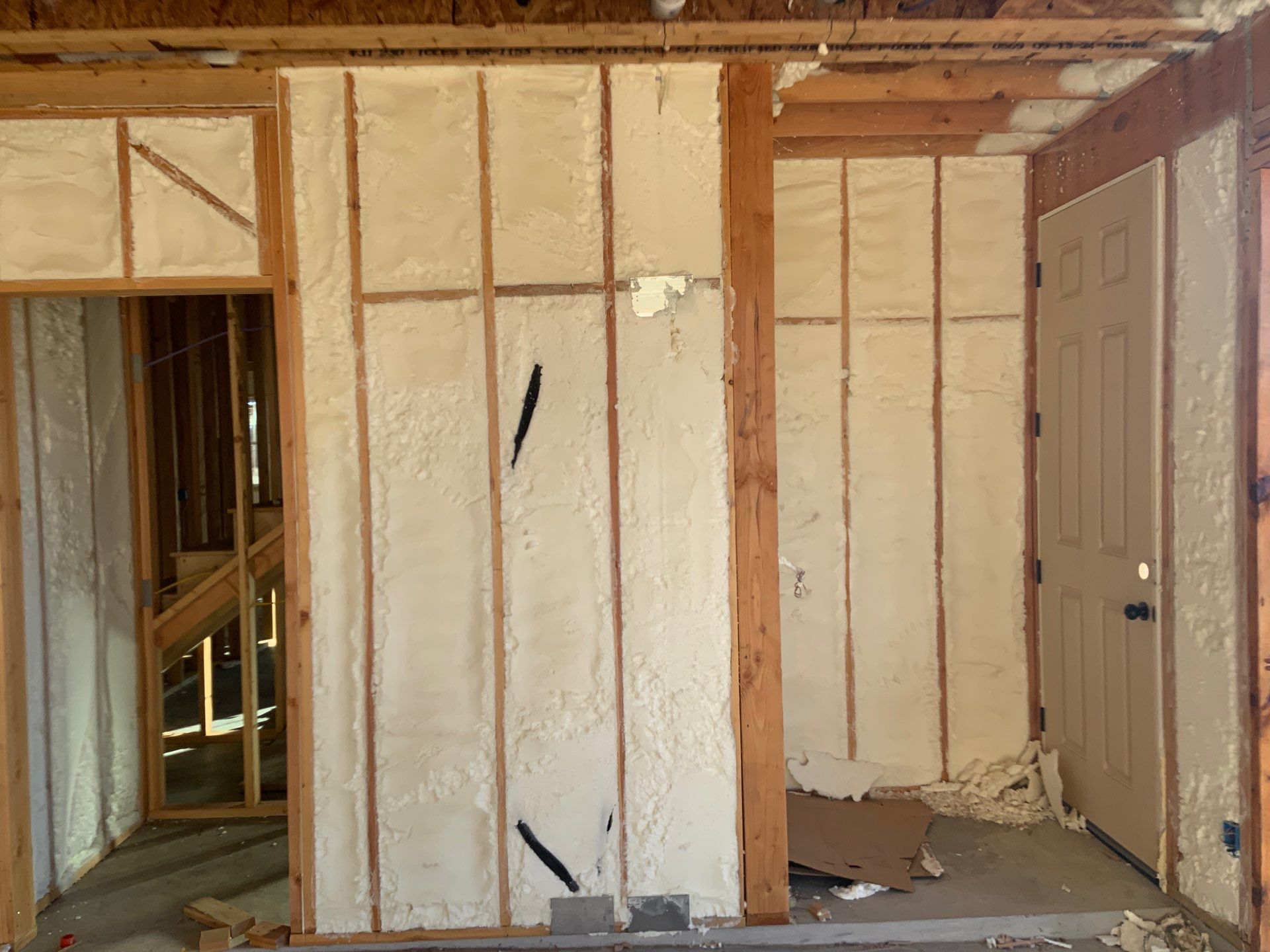 A room with a door and a wall covered in spray foam.