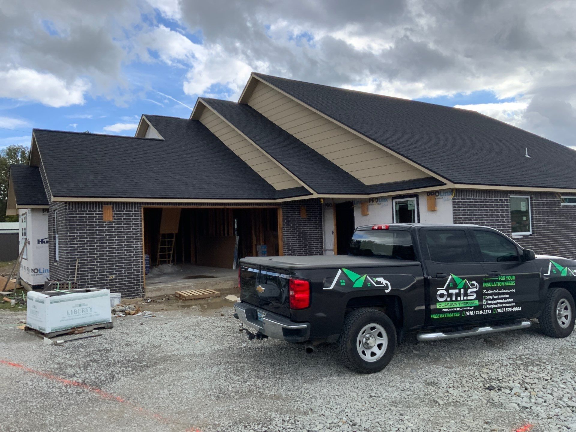 A black truck is parked in front of a house under construction.