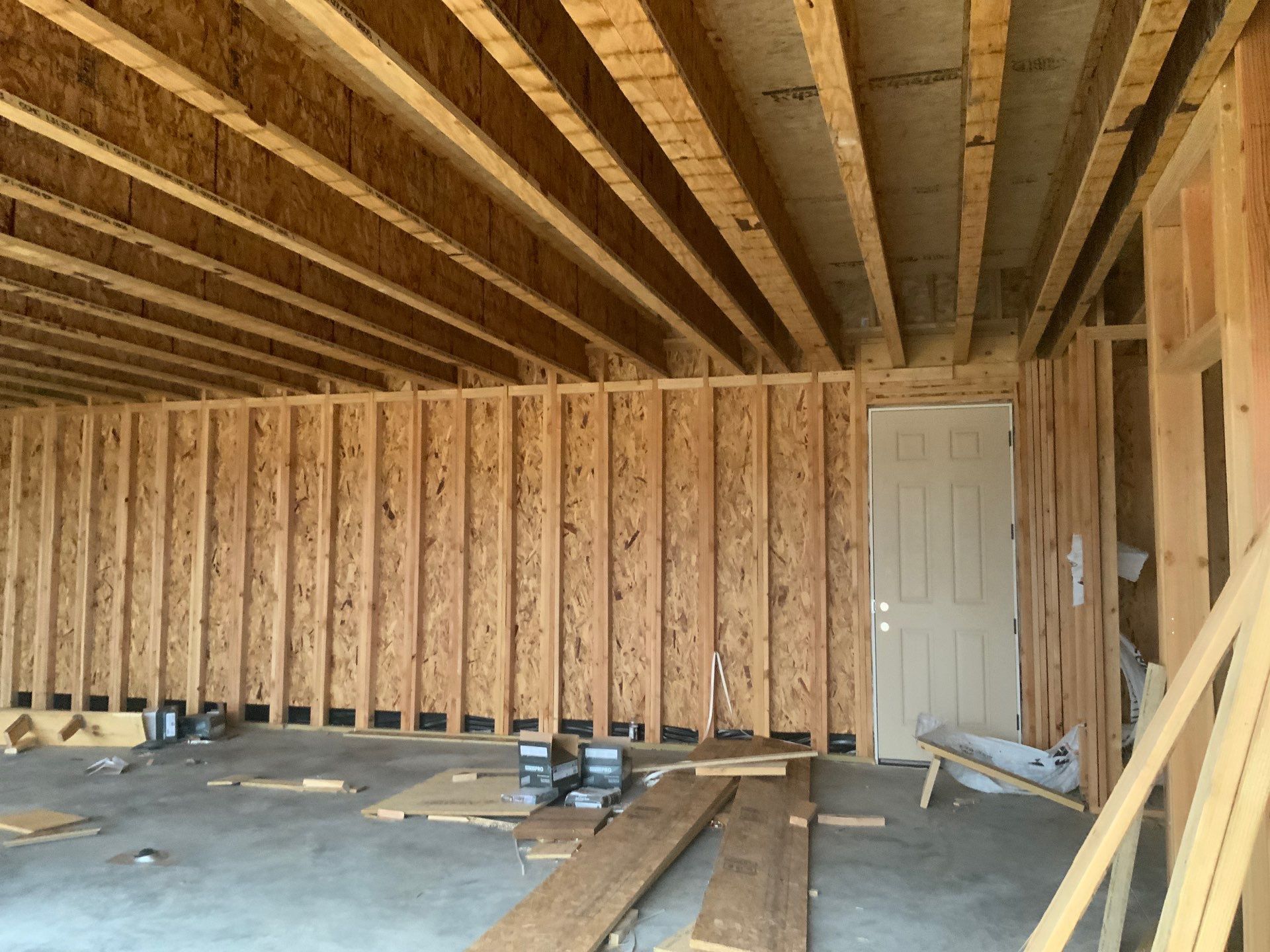 A garage under construction with wooden beams and a door.