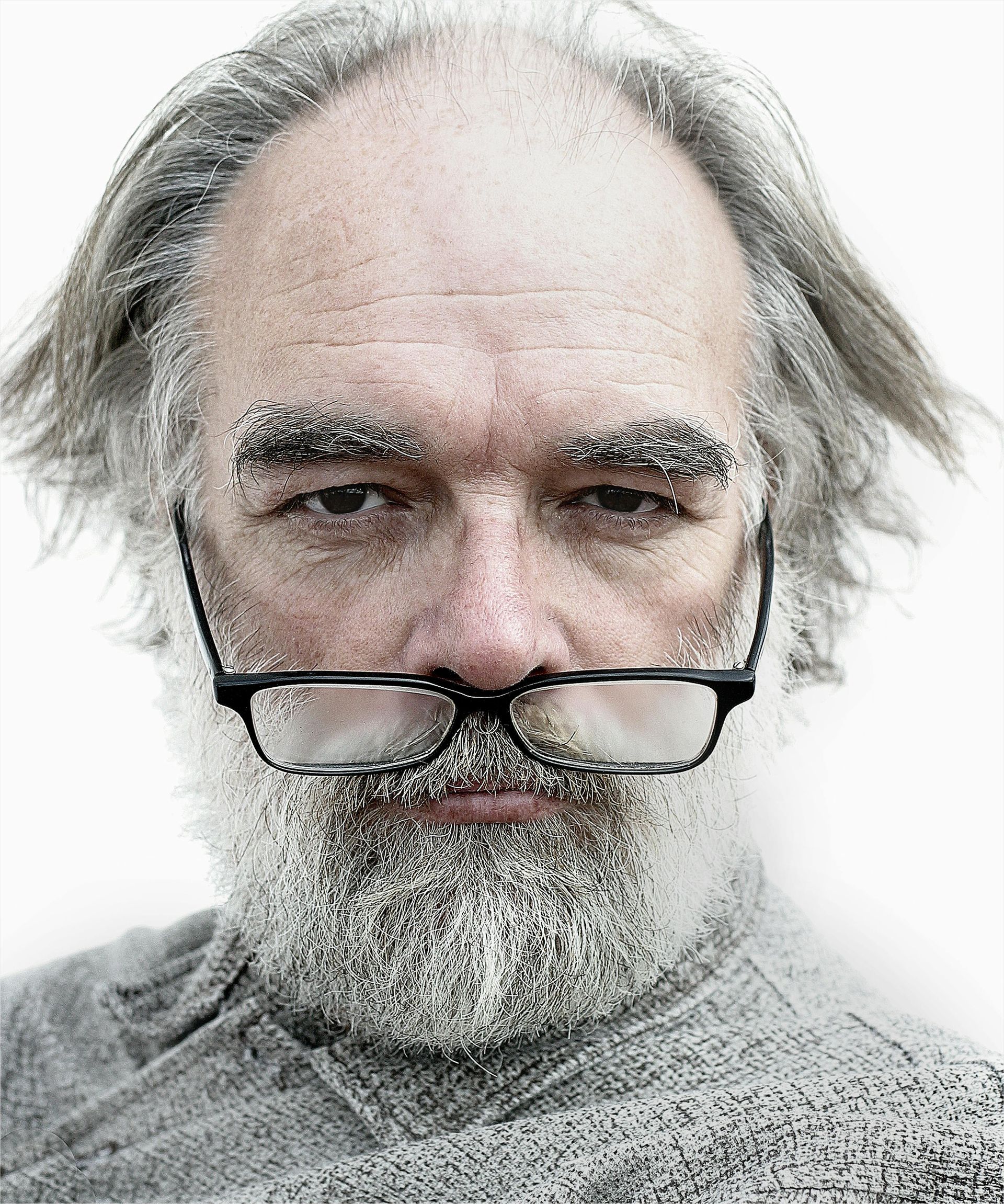 Man with frost-covered beard and eyebrows wearing glasses. Gray hair, serious expression, close-up.