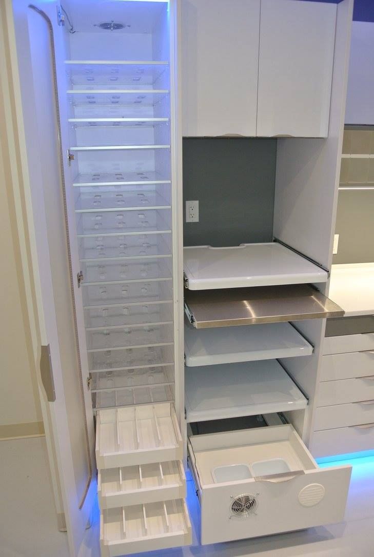 Une armoire blanche avec tiroirs et étagères dans une cuisine.