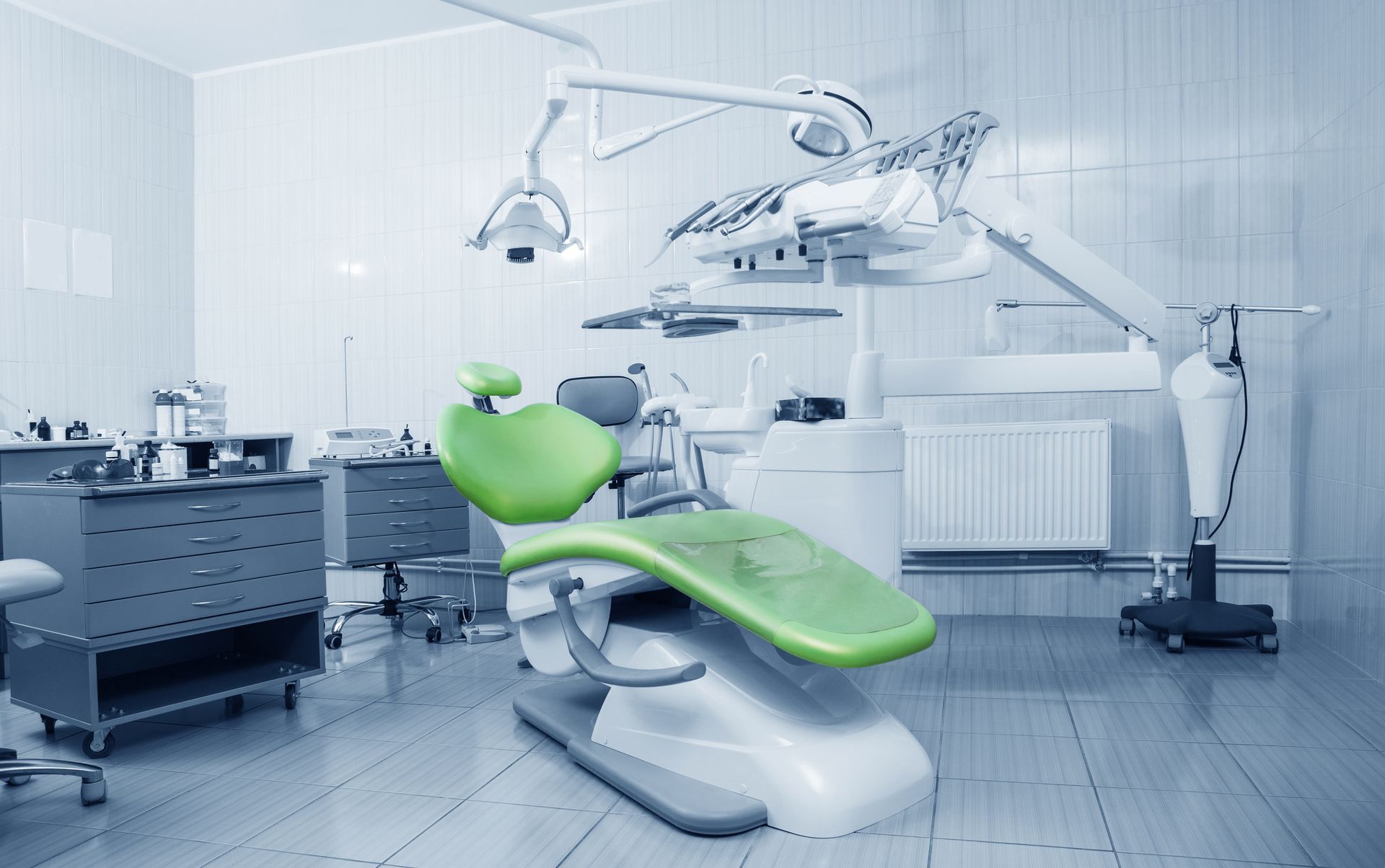 Une chaise dentaire verte est assise dans un cabinet dentaire.
