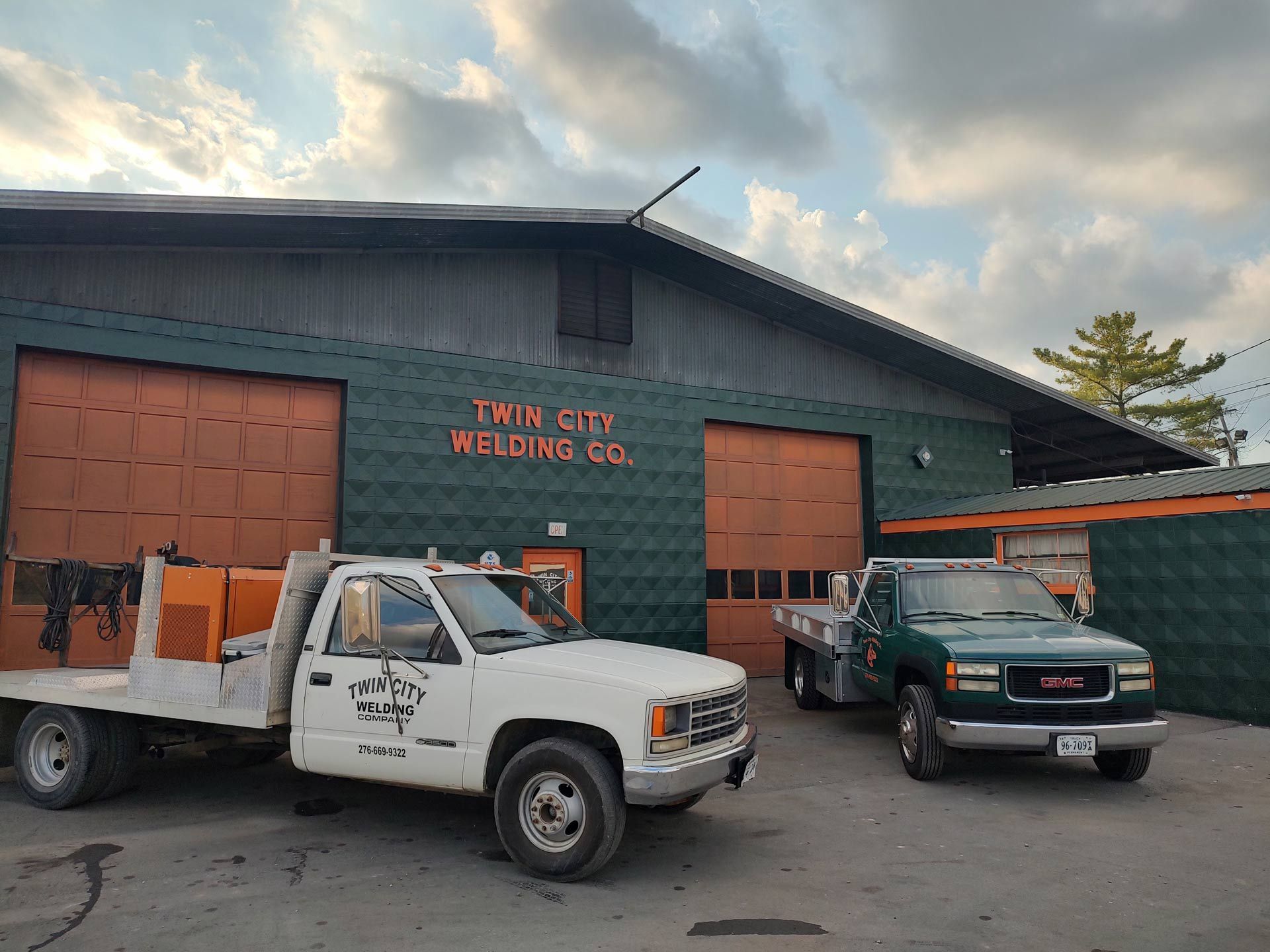 Two trucks are parked in front of a building that says twin city welding