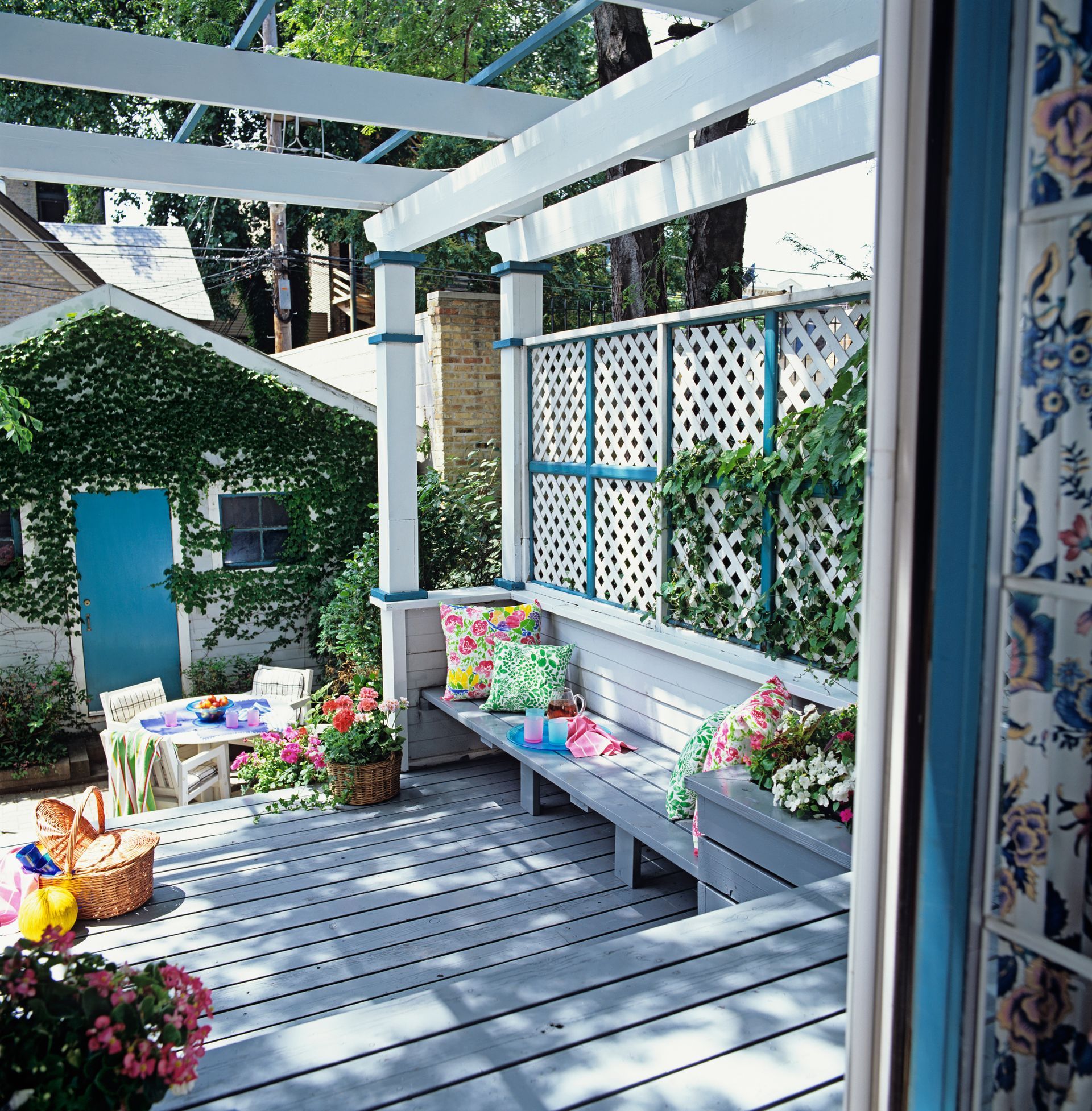 A patio with a bench and chairs under a pergola.