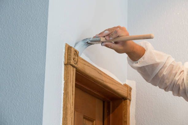 A person is painting a door frame with a brush.