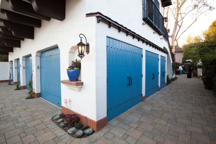 A white house with blue garage doors and a lamp on the side.