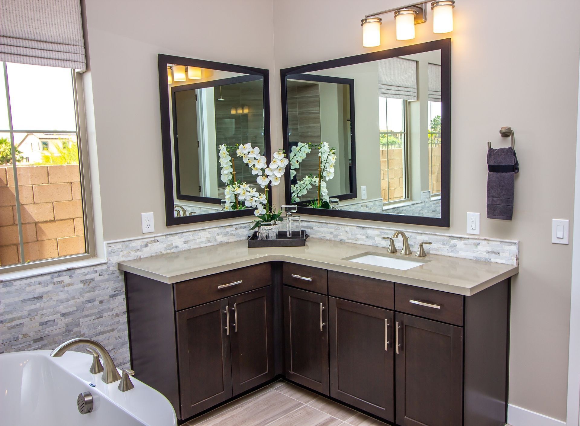 A bathroom with two sinks, two mirrors ,and a bathtub.
