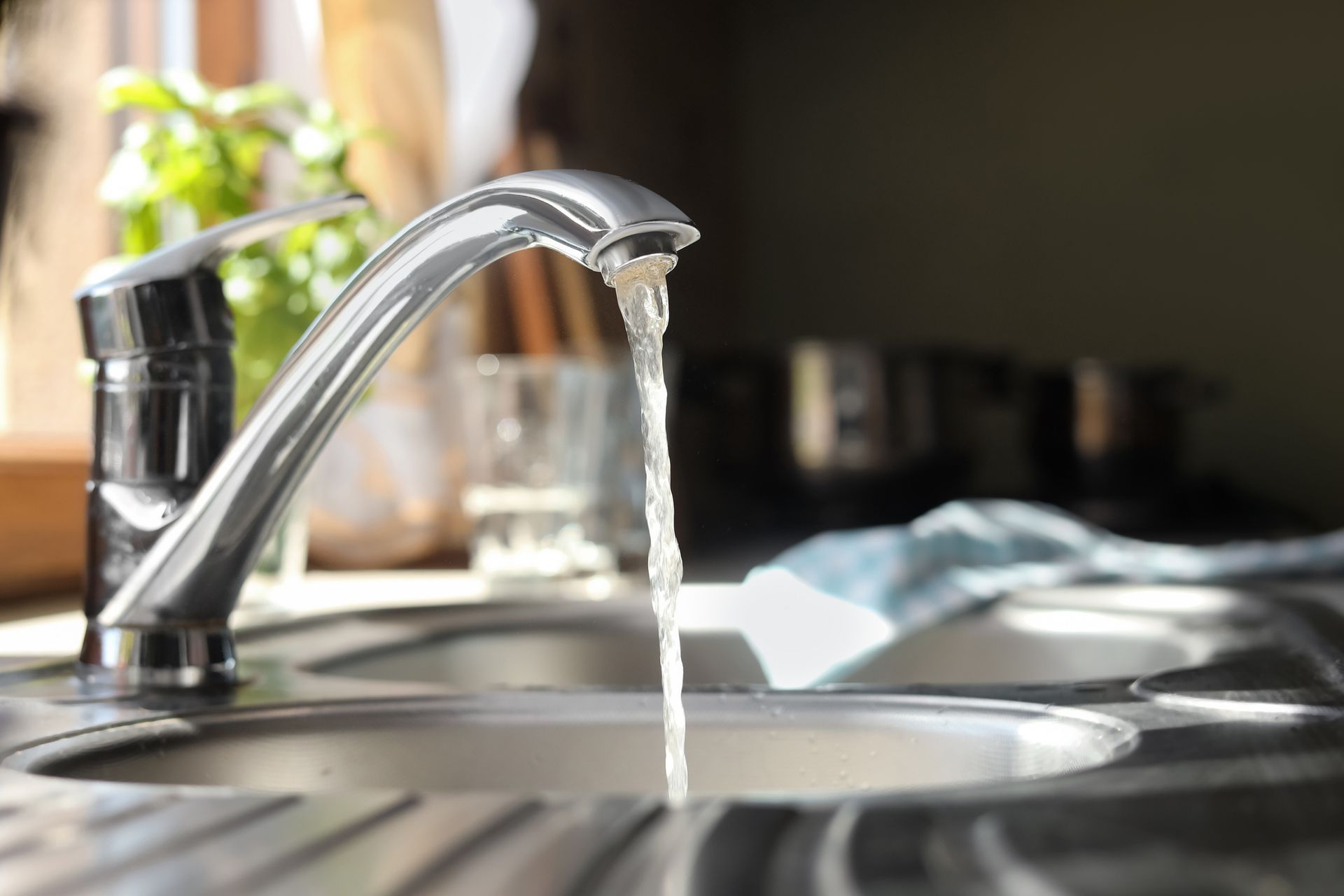 A close-up of a kitchen sink with water running from the faucet. A close-up of a kitchen sink with water running from the faucet.