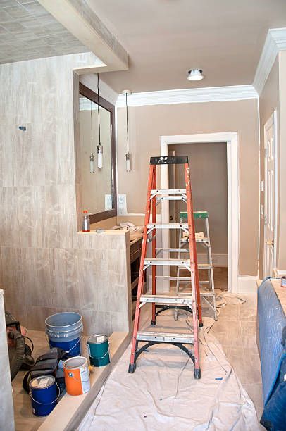 A bathroom under construction with a ladder and buckets of paint.