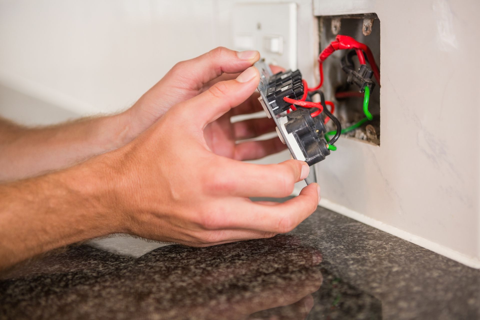 A person is fixing an electrical outlet on a wall.