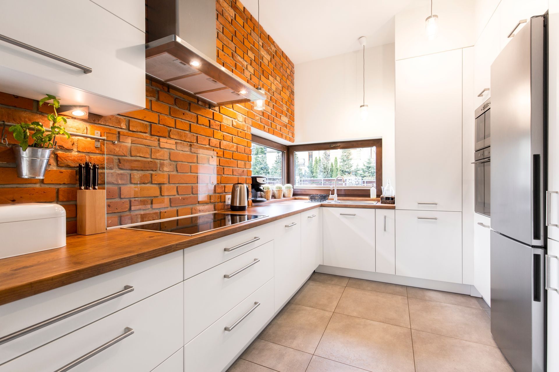 A kitchen with white cabinets and a brick wall.