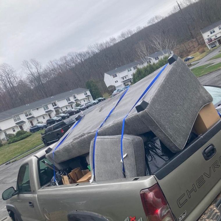 Gray pickup truck overloaded with furniture and boxes in a residential parking lot