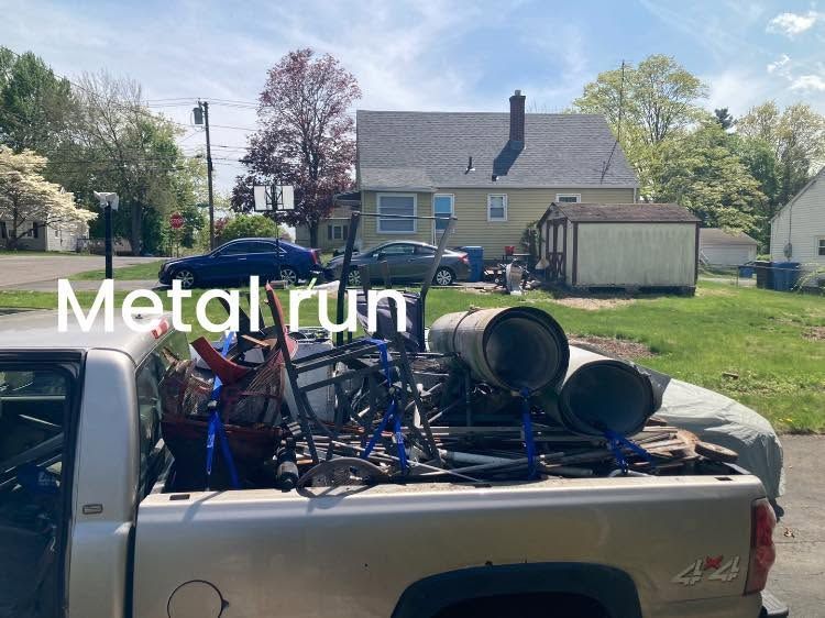 Pickup truck bed filled with metal run scrap and barrels in a suburban yard