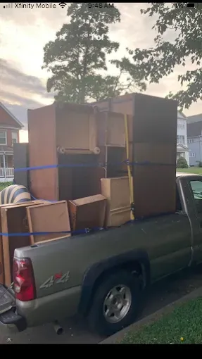 Pickup truck loaded with stacked cardboard boxes in a residential driveway at dusk