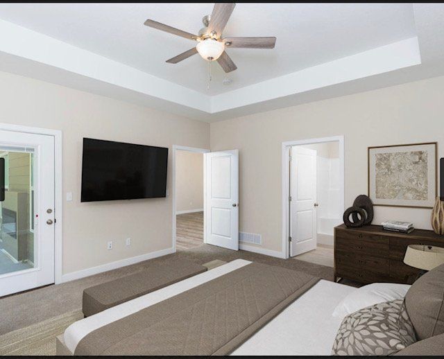 Modern bedroom with a ceiling fan, wall-mounted TV, dresser, and two open doors leading to a bath and closet.
