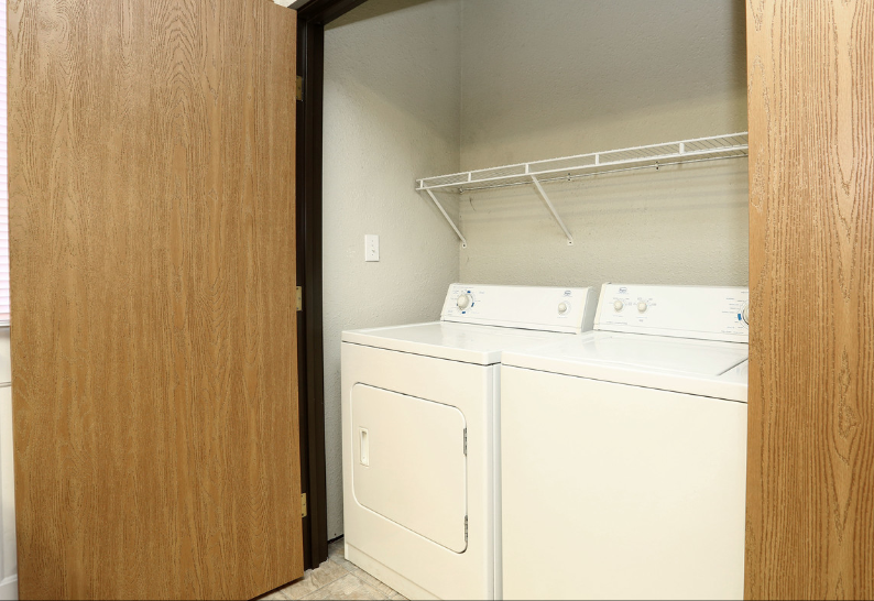 Laundry closet with washer and dryer behind open wooden doors
