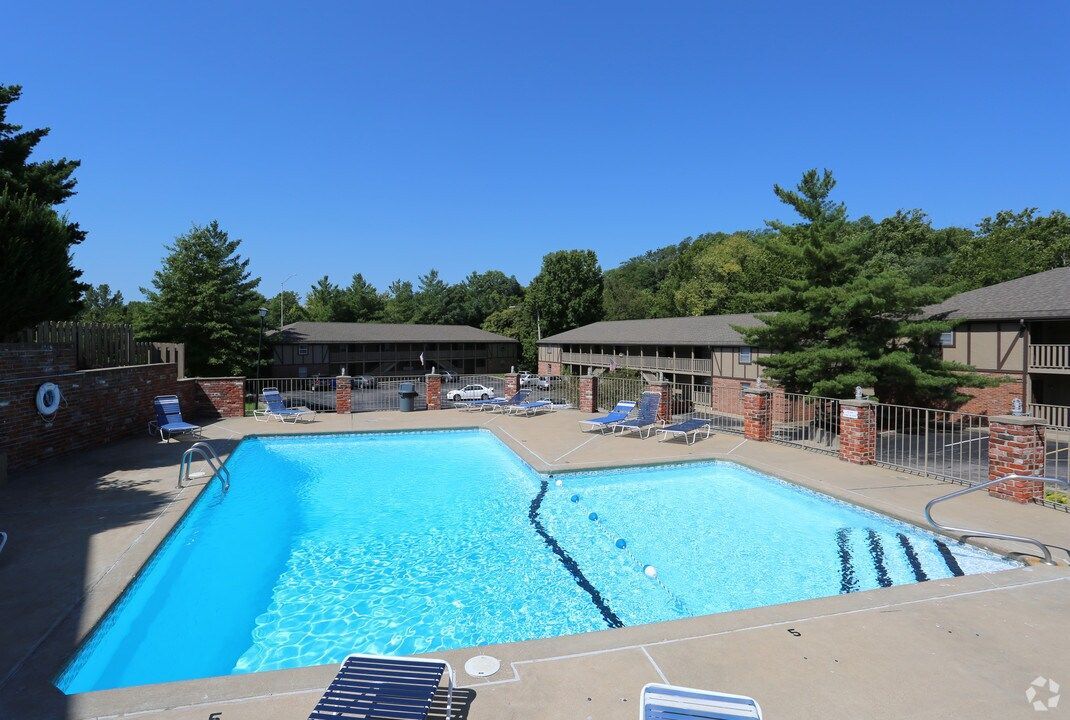Outdoor apartment swimming pool with lounge chairs and clear blue water under a sunny sky
