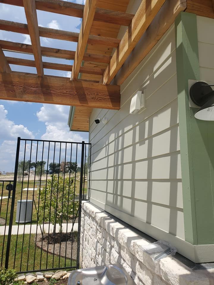 A white house with a black fence and a wooden pergola.