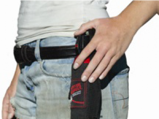 Person wearing jeans and a black belt holding a black holster with a red object.