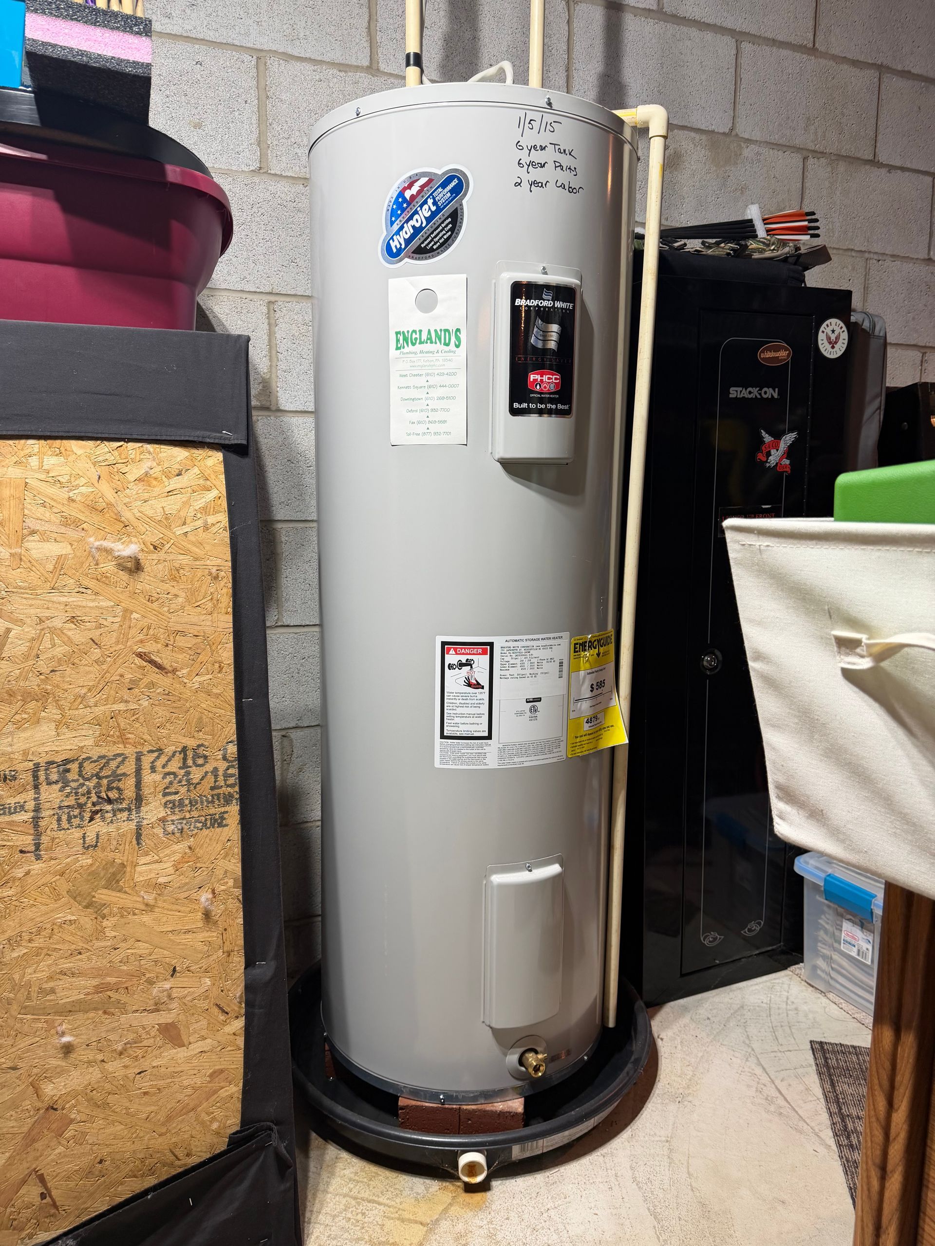 A person is fixing a water heater with a wrench
