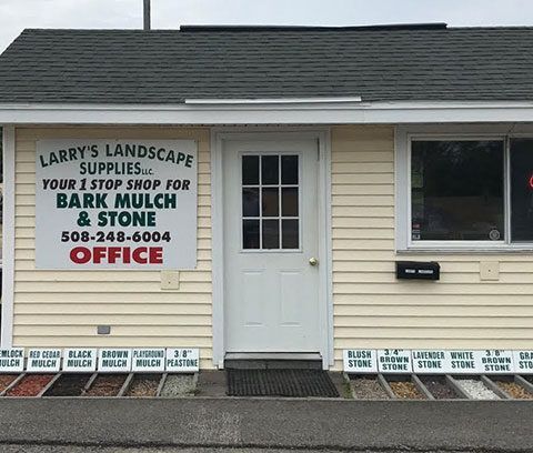 Larry’s Landscape Supplies storefront with white door, window, and large sign advertising bark mulch and stone.