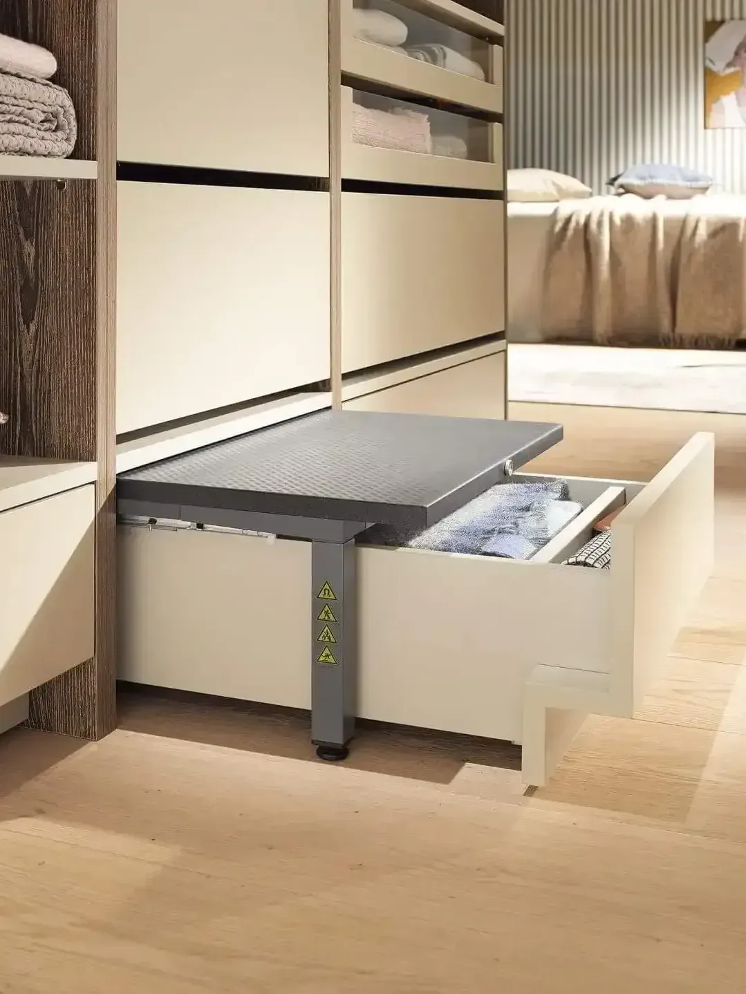 Open drawer bed in a modern bedroom with built-in shelving and light wood floors