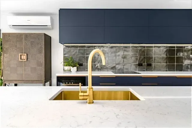 A kitchen with blue cabinets and a gold sink.