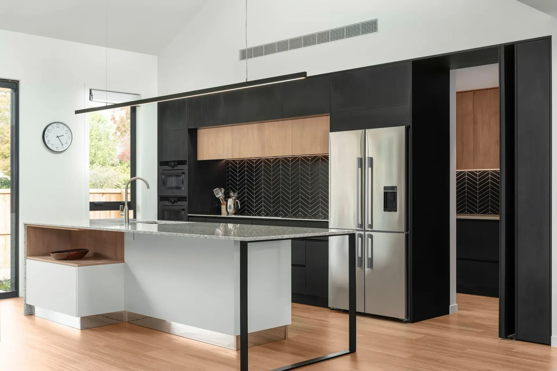 A kitchen with black cabinets , stainless steel appliances and a large island.