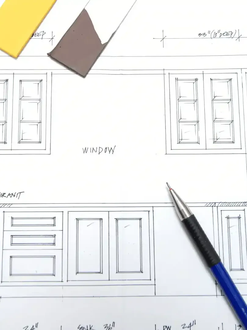 Architectural floor plan sketch with windows and doors, viewed from above, with a blue pen on the page