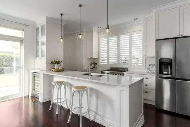 A kitchen with white cabinets , stainless steel appliances and a large island.