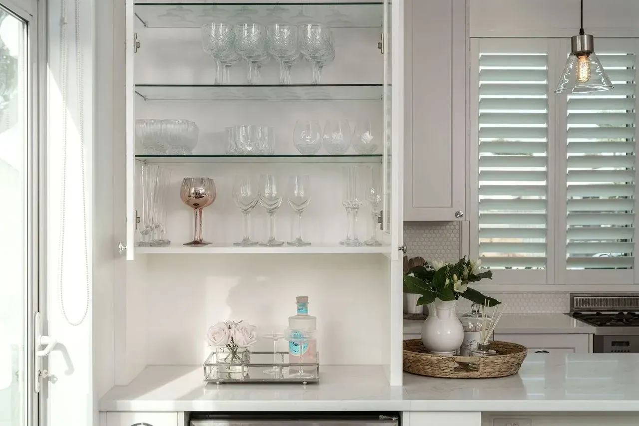 A kitchen with a glass cabinet filled with wine glasses.