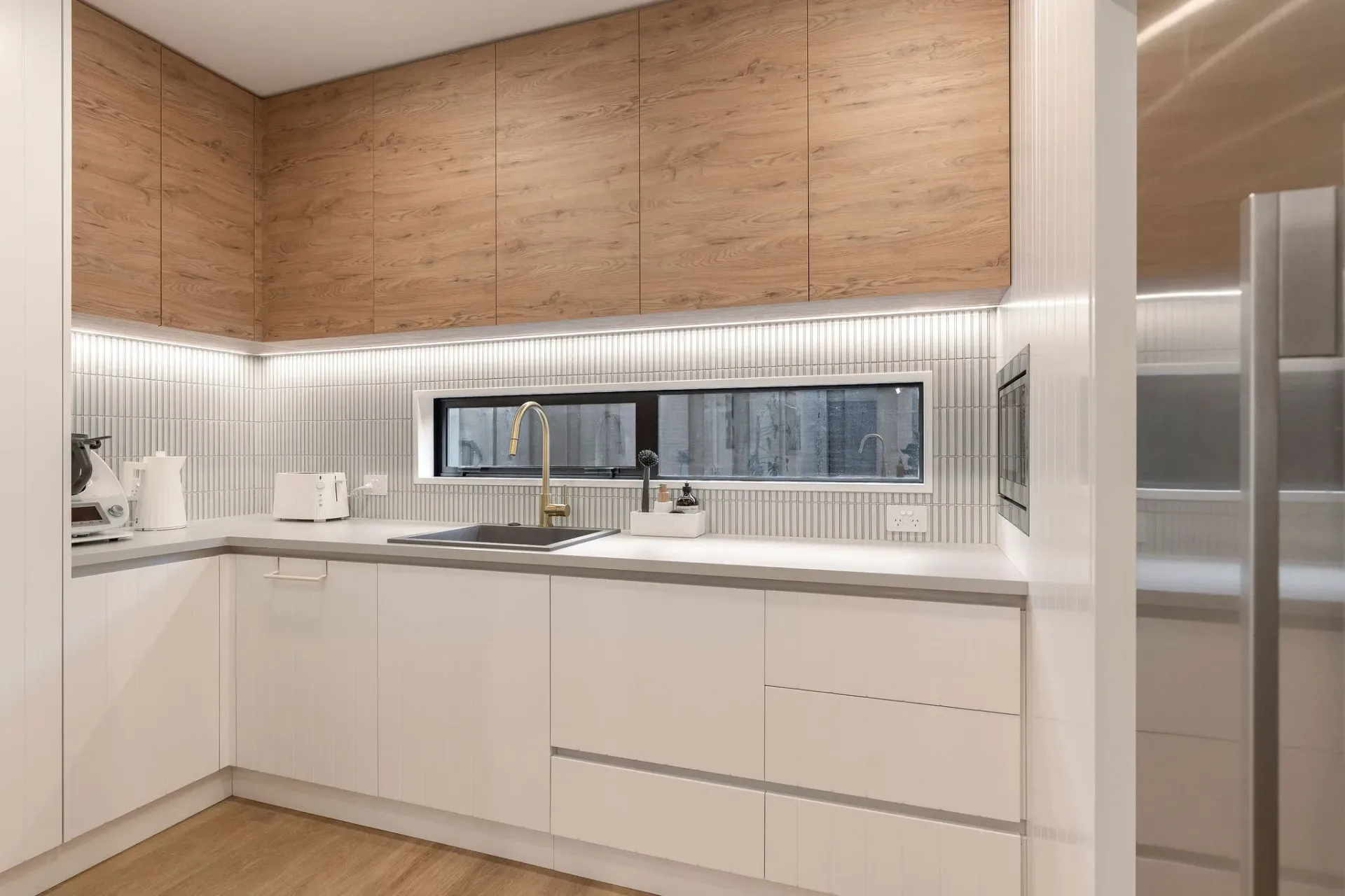 A kitchen with white cabinets and a stainless steel refrigerator.