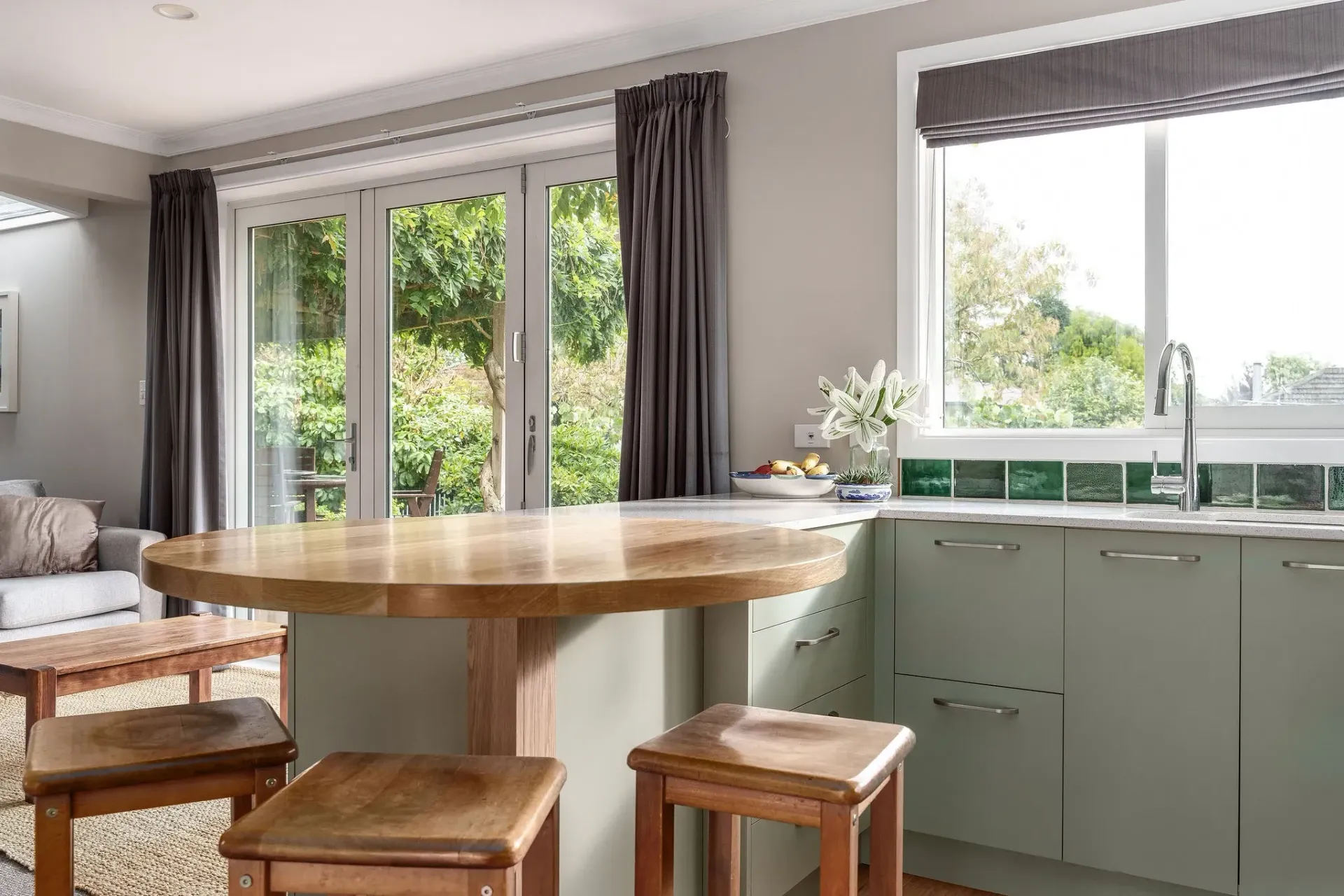 A kitchen with a round table and stools and a sink.