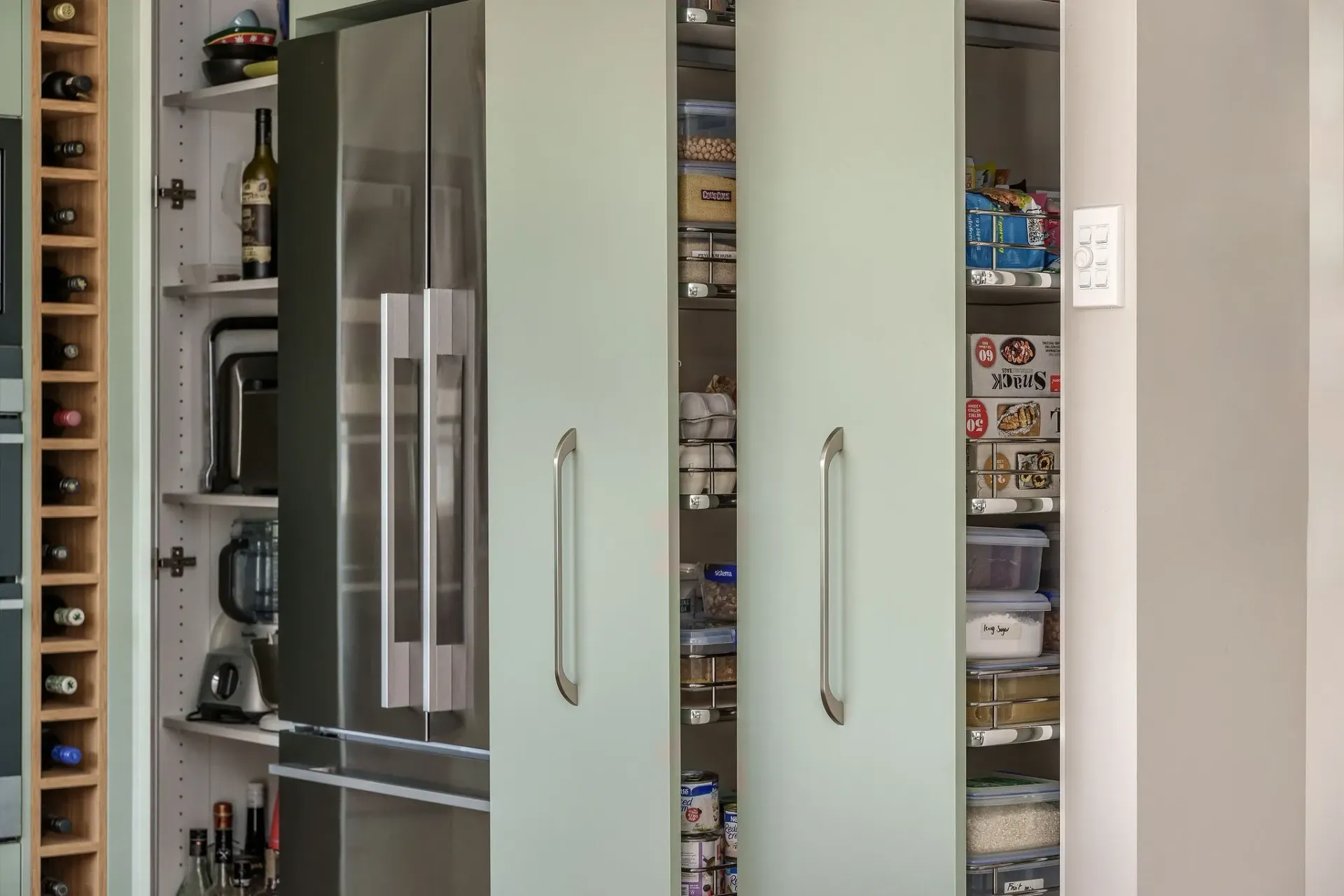 A kitchen with a refrigerator , pantry , and wine rack.