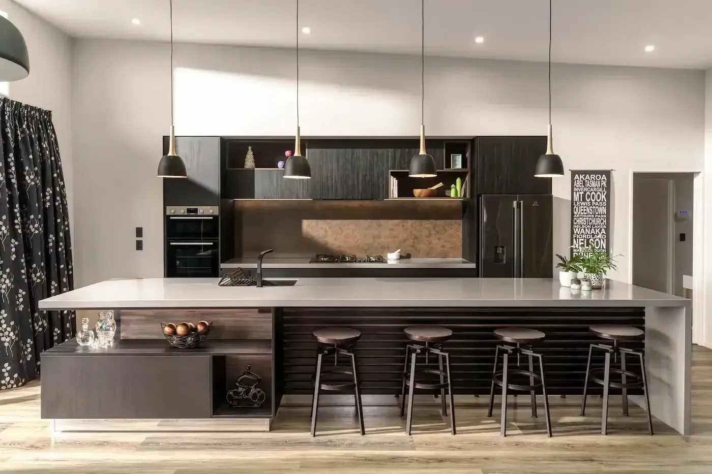 Modern open kitchen with a large island, dark cabinets, pendant lights, and bar stools