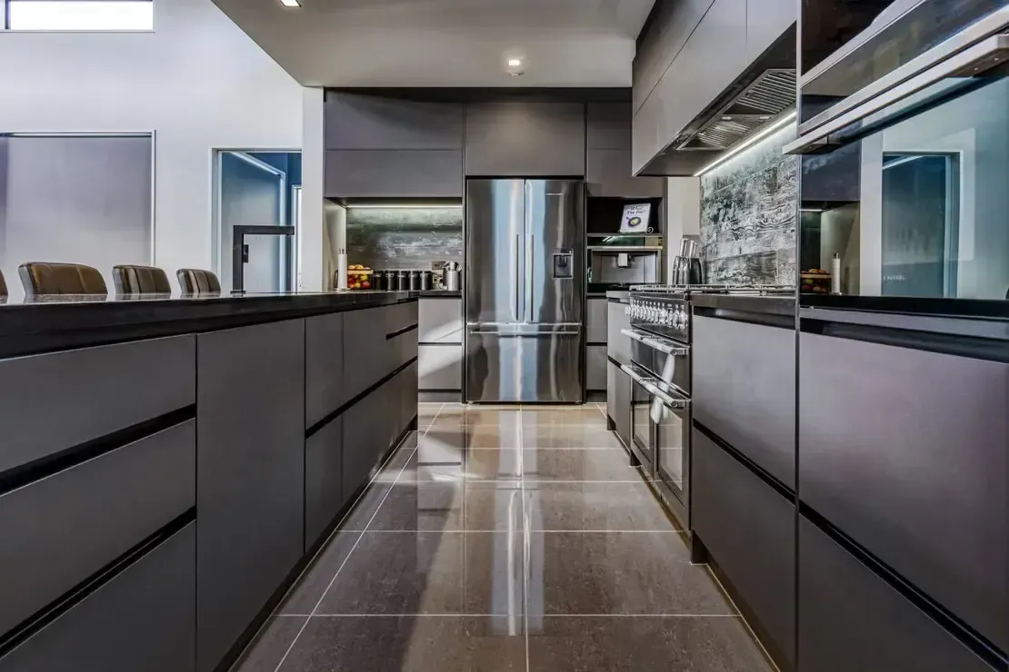 A kitchen with stainless steel appliances and black cabinets.