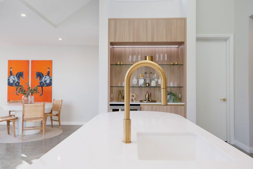 A kitchen with a sink and a dining room in the background