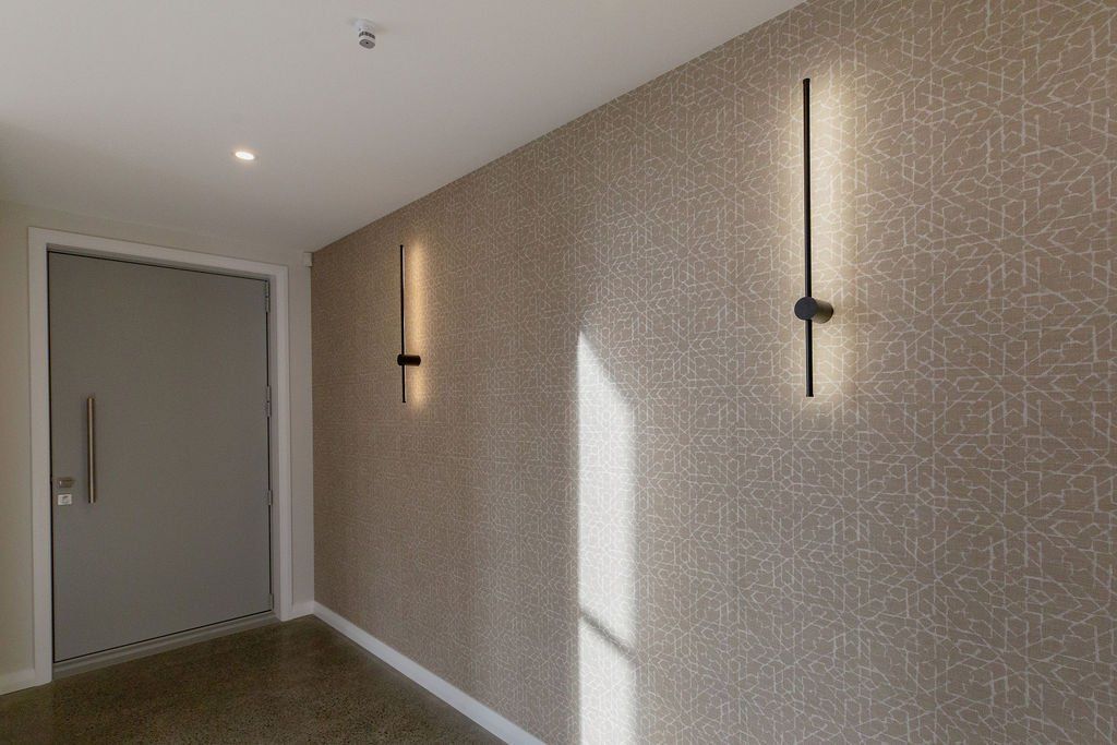 A hallway with a door and two lights on the wall.