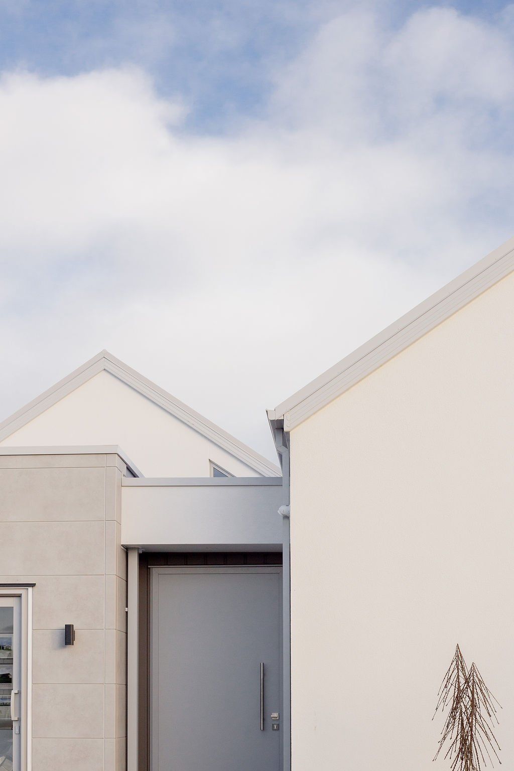 A white house with a gray door and a blue sky in the background
