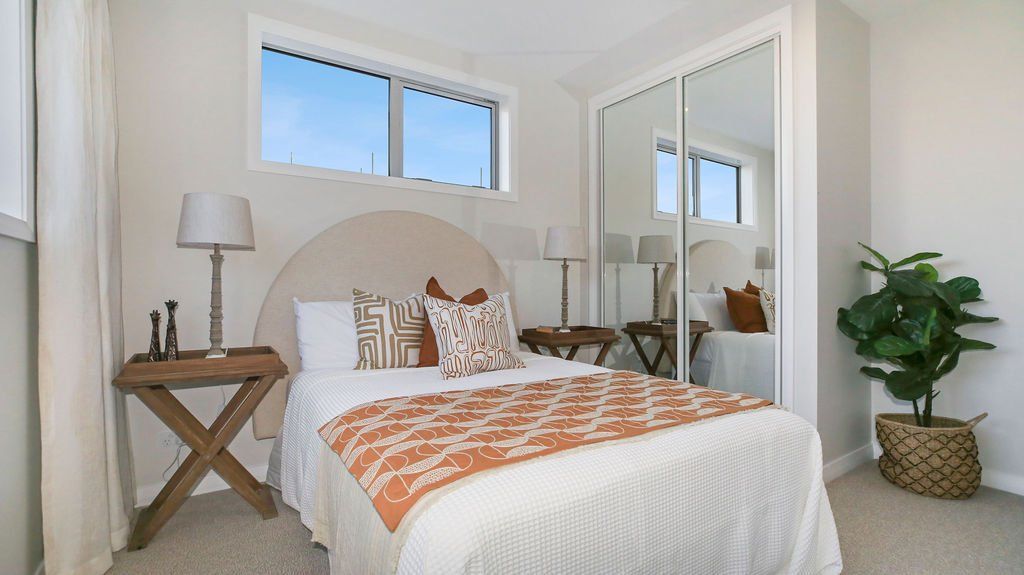 A bedroom with a bed , nightstand , lamp and sliding glass doors.